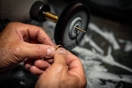 Foto de Goldsmith pulido una joya anillo de oro en su taller de joyería. J) - Imagen libre de derechos