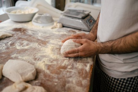 Téléchargez les photos : Plan détaillé des mains d'un boulanger méconnaissable en pétrissant manuellement sur la table d'une boulangerie - en image libre de droit