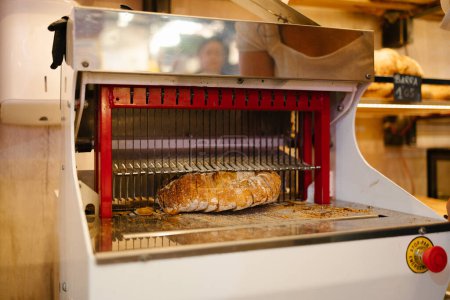 Téléchargez les photos : Pain à l'intérieur de la trancheuse tandis que les lames coupent le pain dans une boulangerie - en image libre de droit