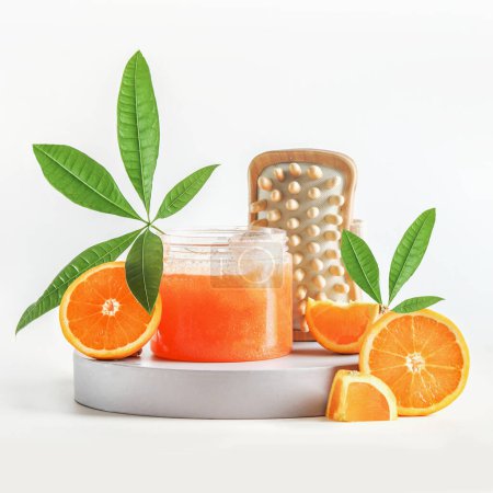 Photo for Spa setting with orange sugar scrub in jar with tropical green leaves, wooden massage brush and orange fruits. Healthy skin care and treatment with natural bath and wellness products. Front view - Royalty Free Image