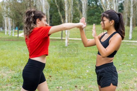 Photo for Two young multiethnic female boxers training outdoors. Boxing sparring and punching workout in a city park. - Royalty Free Image