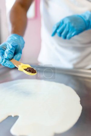 Photo for A worker is preparing a rolled ice cream with milk and chocolate chips on the freeze machine. Concept of new small business - Royalty Free Image