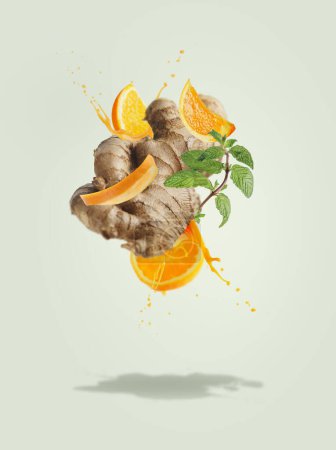 Photo for Flying ginger with orange slices and juice splashing at pale green background mint leaves. Ingredients for refreshing summer drinks. Creative levitation food and drink concept. Front view. - Royalty Free Image