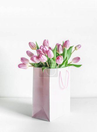 Photo for Bunch of pink blooming tulips in gift box on table at white wall background. Celebrating in mothers day in springtime with beautiful flowers. Front view. - Royalty Free Image
