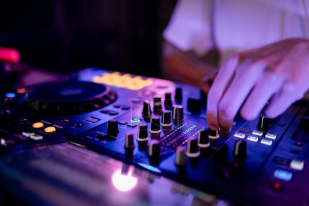 Foto de Primer plano de las manos de DJ trabajando usando mesa de mezclas en un club - Imagen libre de derechos
