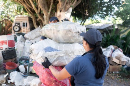 Téléchargez les photos : Une femme hispanique non identifiée empile des sacs de matériaux recyclés, contribuant ainsi à des efforts durables avec un impact considérable - en image libre de droit