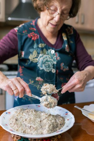 Téléchargez les photos : Photo verticale d'une patiente âgée enrobant la pâte à croquette de farine et d'oeuf - en image libre de droit