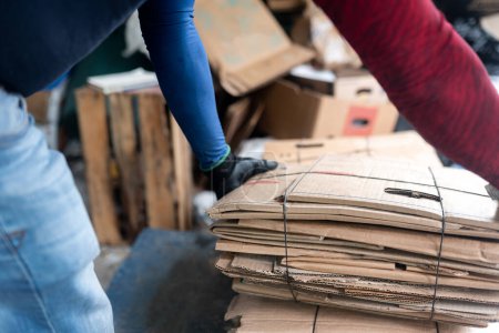 Téléchargez les photos : Vue rapprochée des mains d'un homme hispanique mesurant méticuleusement le carton dans une installation de recyclage - en image libre de droit