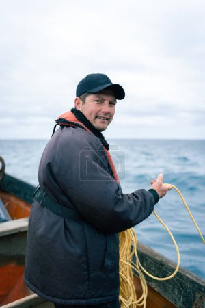 Geduldiger Hummerfischer hält ein Seil auf einem Boot, das bereit ist, es zurückzuziehen