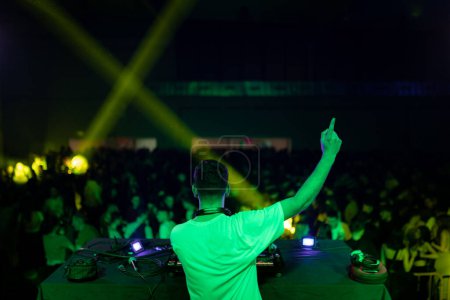 Rear view of DJ gesturing during a performance in a club