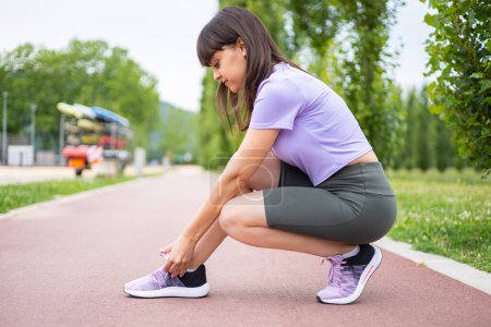 Photo for Sport woman tying shoe for fitness training outdoors. Exercise and active lifestyle. - Royalty Free Image