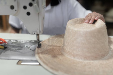 Photo for Sewing a traditional palm tree hat using a sewing machine - Royalty Free Image