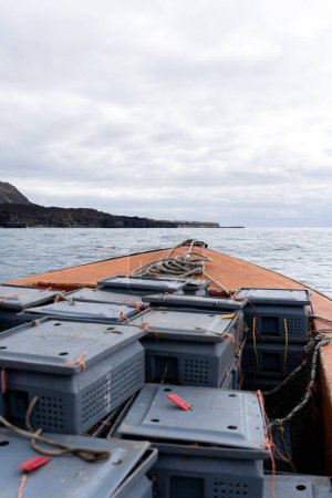 Vertikale Aufnahme eines Decks eines Hummer-Fischerbootes, gefüllt mit Containern mit gefangenen Hummern ohne Menschen