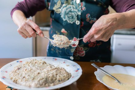 Téléchargez les photos : Gros plan des mains âgées d'une grand-mère méconnaissable enrobant la pâte à croquette de farine et d'oeuf - en image libre de droit