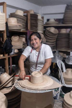 Eine erwachsene hispanische Frau lächelt, während sie in einer traditionellen Hutfabrik in Guatemala arbeitet