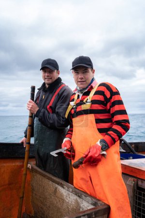 Retrato vertical de dos pescadores en un barco de pesca de langosta trabajando juntos