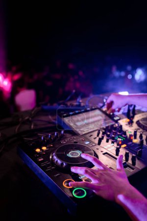 Gros plan vertical des mains d'un jeune DJ masculin se produisant sur scène dans une discothèque