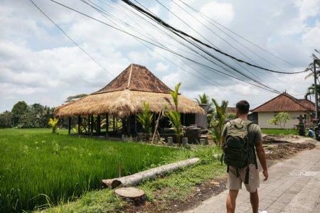 Téléchargez les photos : Jeune routard marchant à travers un village en Asie du Sud-Est, observant les rizières. Ubud, Bali - en image libre de droit