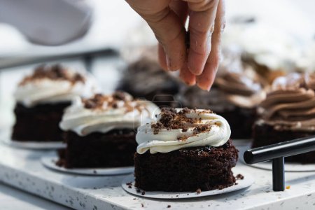 Foto de Cosecha irreconocible cocinar espolvorear apetitoso pastel de esponja vegana con chocolate mientras se cocina en la cocina de panadería - Imagen libre de derechos