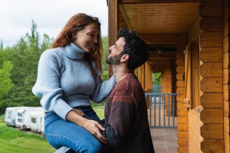Positives Paar von Reisenden, die sich auf der Terrasse eines Holzhauses entspannen und sich beim Urlaub in den Pyrenäen anschauen