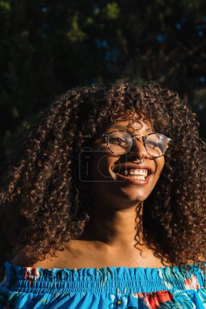 Photo for Stylish black female with curly hair laughing and looking away on summer day - Royalty Free Image