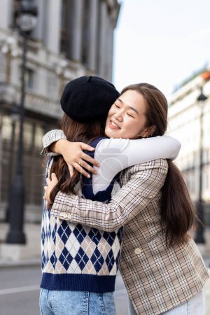 Téléchargez les photos : Two Asian female friends meeting and hugging each other on the city street - en image libre de droit