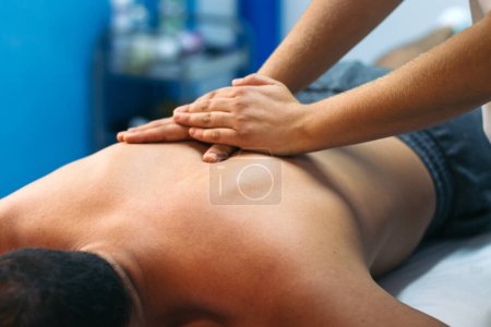 Téléchargez les photos : Jeune femme soignant un patient masculin. physiothérapie de massage du dos. gros plan - en image libre de droit
