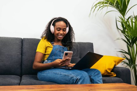 Junge schwarze Frau genießt ihren digitalen Lebensstil zu Hause, perfekt für technologiebezogene Inhalte und Marketing