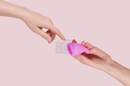 Téléchargez les photos : Main féminine avec coupe menstruelle réutilisable sur fond rose - en image libre de droit