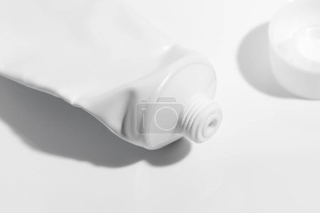Tubo vacío usado con tapa blanca abierta, plantilla de maqueta para pasta de dientes, crema, gel o champú, paquete en blanco sobre fondo blanco