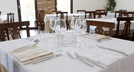 Photo for Restaurant table set up with tableware and wine glass. Interior of italian restaurant - Royalty Free Image