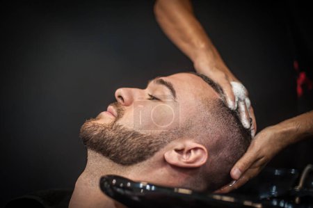 Téléchargez les photos : Salon de coiffure urbain moderne coiffeur lave les cheveux d'un client dans un salon de coiffure professionnel et studio. Vue détaillée en gros plan - en image libre de droit
