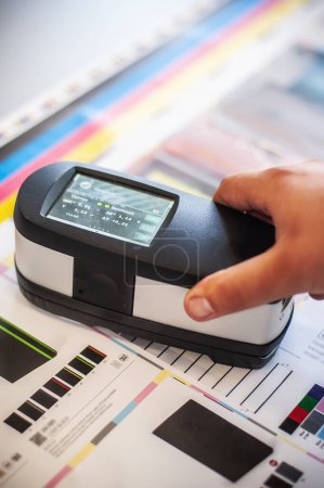X-Rite handheld spectrophotometer verify color patches, modern press shop prepress department.