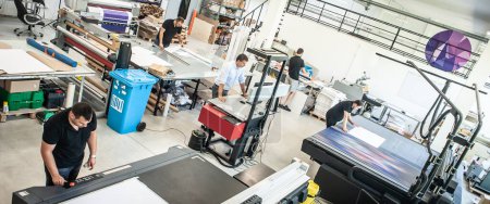 In einer großen modernen Druckerei arbeiten die Bediener an verschiedenen Maschinentypen für Drucksachen