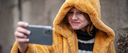 Porträt der stilvollen gut aussehenden Teenage-Bloggerin, Lifestyle-Internet-Influencerin beim Selfie, Handy in der Hand.