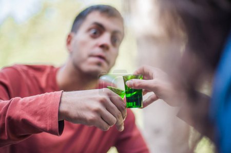 Photo for Cheers. Very drunk couple, a boy and a girl, chug shot drink from small glasses. Express drinking and fast get drunk concept - Royalty Free Image