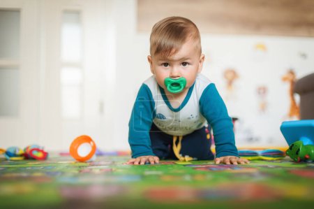 Photo for Cute baby boy crawls on the home floor, explore the world and learn to move. Front view. Love and family emotion - Royalty Free Image