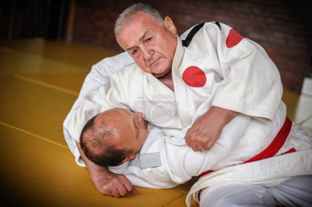 Photo for Judo sensei master instructor in traditional gi kimono demonstrate judo ground technique on tatami - Royalty Free Image