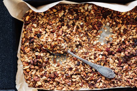 Homemade granola with nuts and raisins in a baking tray.