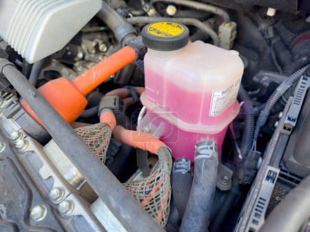 Photo for Reservoir coolant bottle in car engine compartment made of durable translucent plastic. - Royalty Free Image