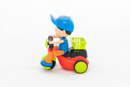 Plastic toy boy riding colorful plastic tricycle with delivery box isolated on white background