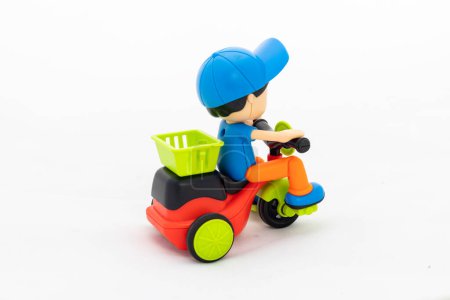 Toy boy with cap riding cycle isolated on white background