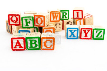 Alphabet-Holzklötze mit ABC-Alphabeten selektiv fokussiert auf weißem Hintergrund