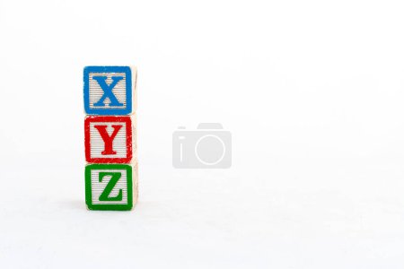 Bloques de alfabetos XYZ apilados y aislados sobre fondo blanco con espacio de copia.