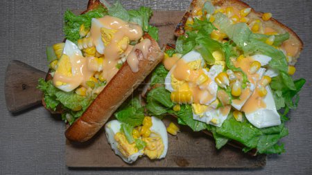 French baguette with egg, lettuce and mayonnaise filling on a cutting board