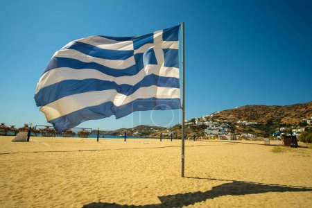 Téléchargez les photos : Vue d'un magnifique drapeau national grec soufflant dans le vent sur la plage de Mylopotas à Ios en Grèce - en image libre de droit