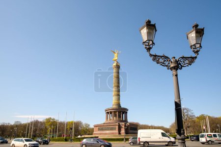 Foto de Berlín, Alemania - 19 de abril de 2023: Vista de la hermosa Columna de la Victoria en Berlín Alemania, coches y una lámpara de calle decorada en Berlín Alemania - Imagen libre de derechos