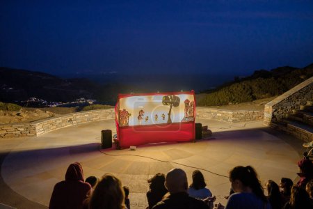 Photo for Ios, Greece - September 10, 2023 : View of a traditional puppet show at Odysseas Elytis outdoor theatre and the famous Mylopotas beach in the background in Ios Greece - Royalty Free Image