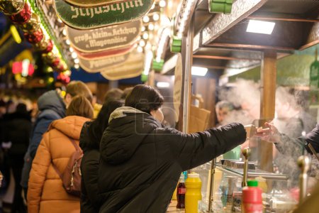 Foto de Bonn, Alemania - 16 de diciembre de 2023: Vista de la gente que compra salchichas tradicionales alemanas en el Mercado de Navidad en Bonn Alemania - Imagen libre de derechos