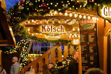 Foto de Bonn, Alemania - 16 de diciembre de 2023: Vista de un bar de Navidad iluminado que vende Klsch, la famosa cerveza de Colonia en el mercado de Navidad de Bonn Alemania por la noche - Imagen libre de derechos